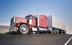 Red semi truck hauling a refrigerated trailer on the highway.