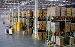 Large warehouse with towering pallet racks and a forklift in the aisle.