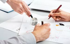 Business partners reviewing pie charts and graphs with pens in hand.