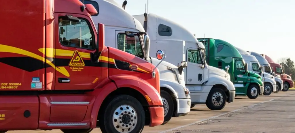 Row of semi-trucks in red, white, and green parked side by side.