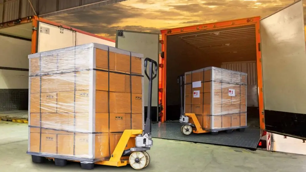 Wrapped pallets loaded into a shipping container with a pallet jack.