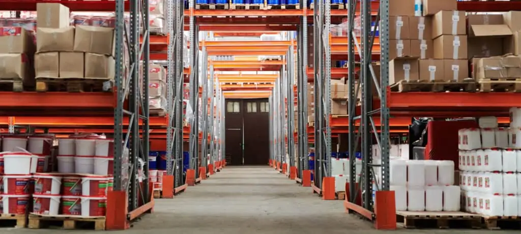 Warehouse aisle lined with stacked pallets and storage racking