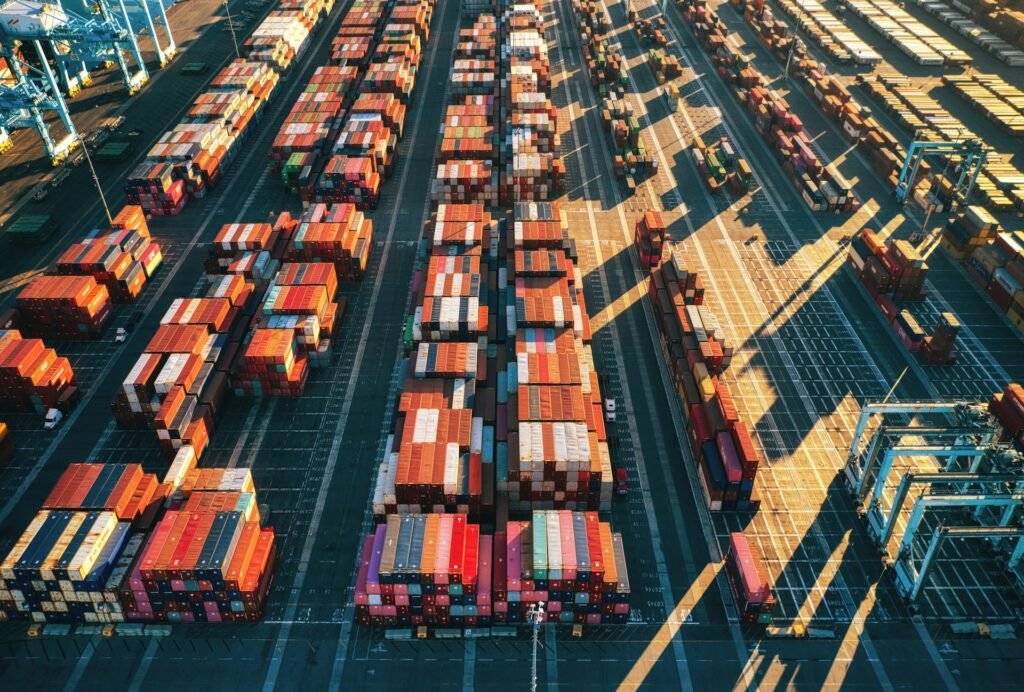 Aerial view of stacked shipping containers at a busy port terminal.